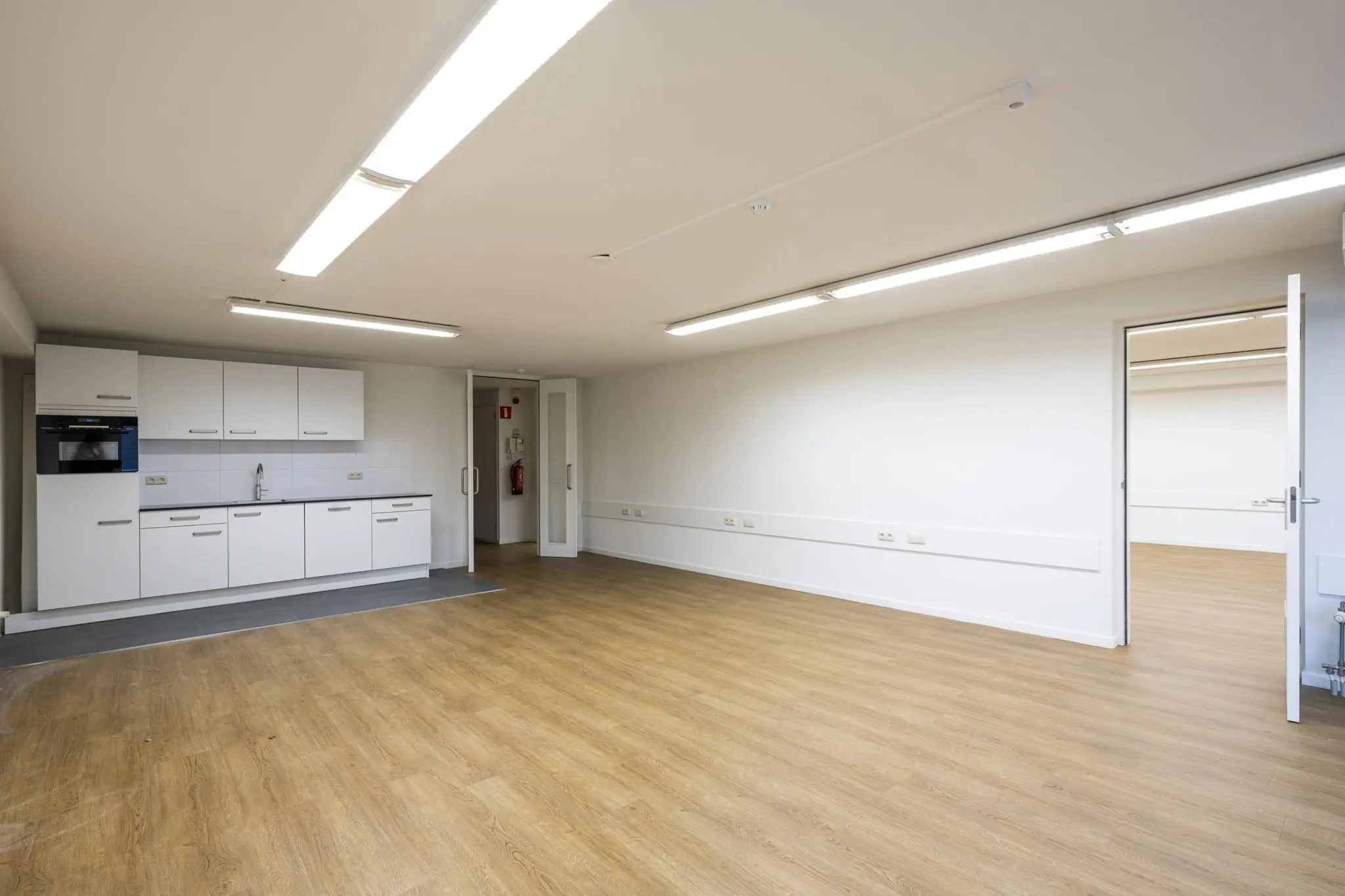 Lichte, lege ruimte met een keukenblok en houten vloer aan de Prins Hendrikkade.